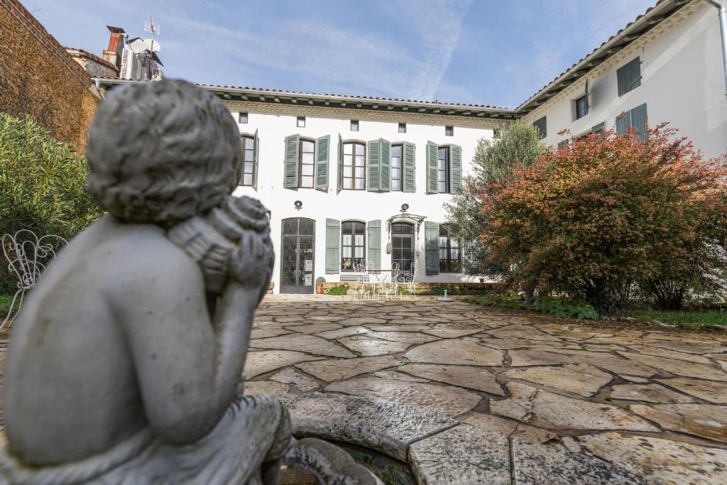 Una statua di una ragazza seduta davanti a un edificio di La Maison d'Augustin a Mont-de-Marsan