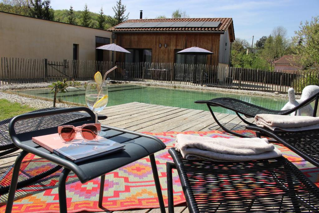 une terrasse avec une table, un livre et des lunettes de soleil dans l'établissement Magnifique gîte écologique en pleine campagne avec piscine, à Pont-du-Casse