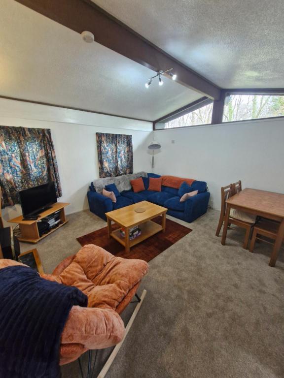 a living room with a blue couch and a table at 57 penlan holiday park in Cenarth