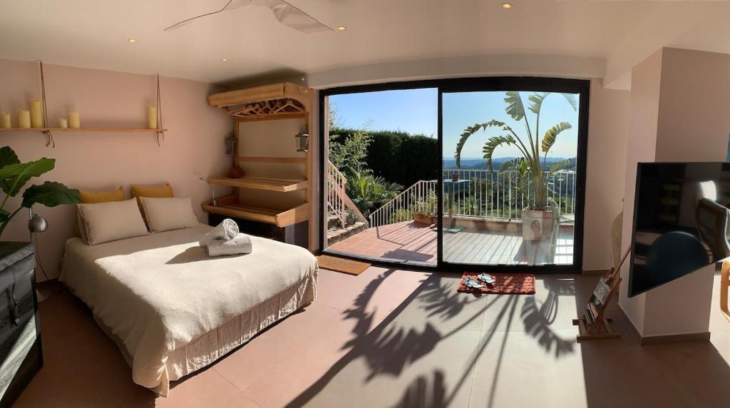 une chambre avec un lit et une grande fenêtre en verre dans l'établissement loft jacuzzi sauna pool yoga sea view love-room, à Saint-Jeannet