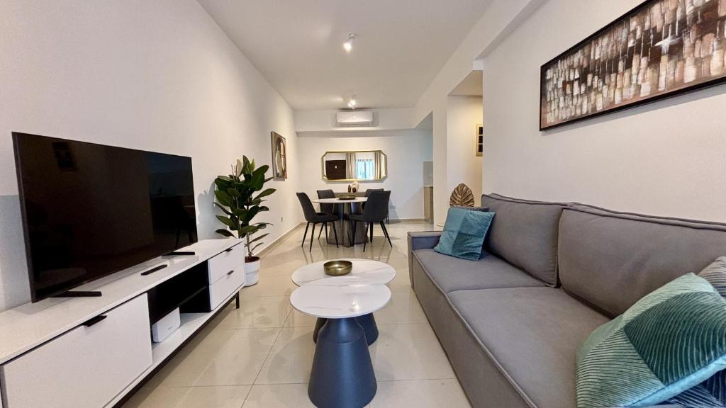 Una sala de estar con un sofá y un televisor de pantalla plana. en Zavos Aqua Park Club Apt by TrulyCyprus, en Limassol