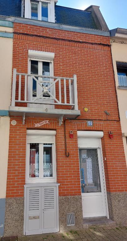 - un bâtiment en briques avec deux fenêtres et un chien sur un balcon dans l'établissement Maison de pêcheur LE TREPORT 