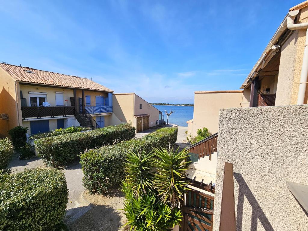 - une vue sur un bâtiment avec des buissons et des arbres dans l'établissement Bel appartement climatisé vu sur l'étang, à Leucate-Plage