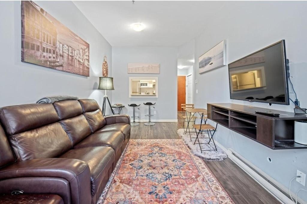 un salon avec un canapé et une télévision à écran plat dans l'établissement Cozy 1 Bedroom Downtown Central, à Vancouver