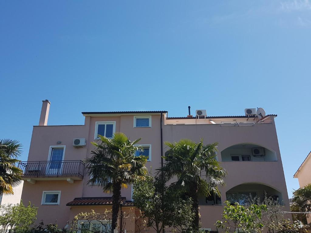 a building with palm trees in front of it at Apartment Studio Baric in Poreč