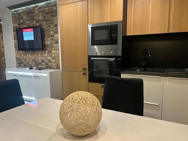 a kitchen with a white table with chairs and appliances at Apartament z dwoma sypialniami i tarasem in Płock