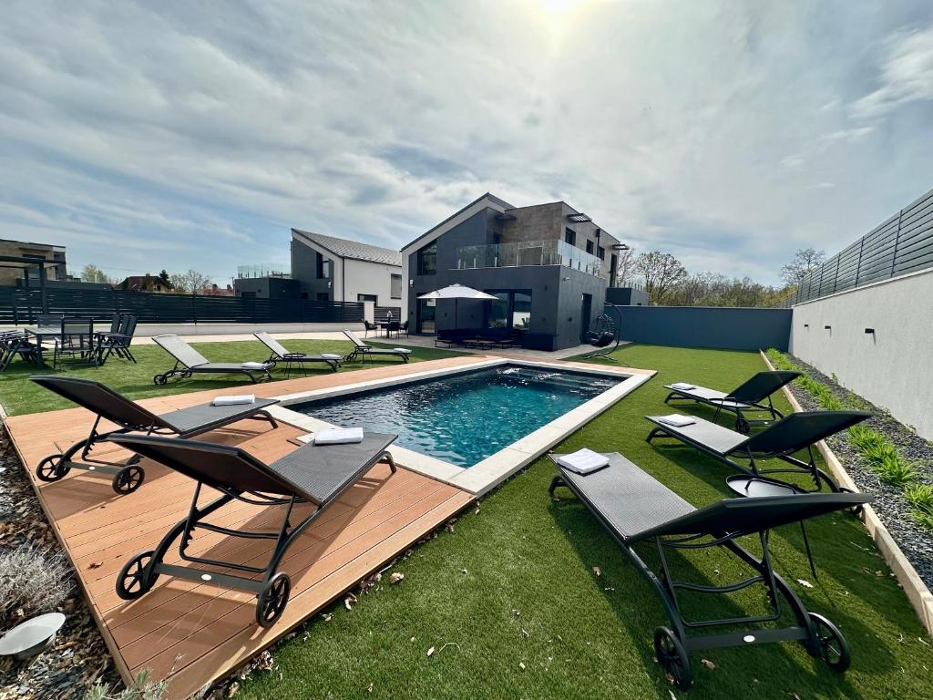 a backyard with a pool and chairs and a house at Villa Porta Verde I in Balatonalmádi