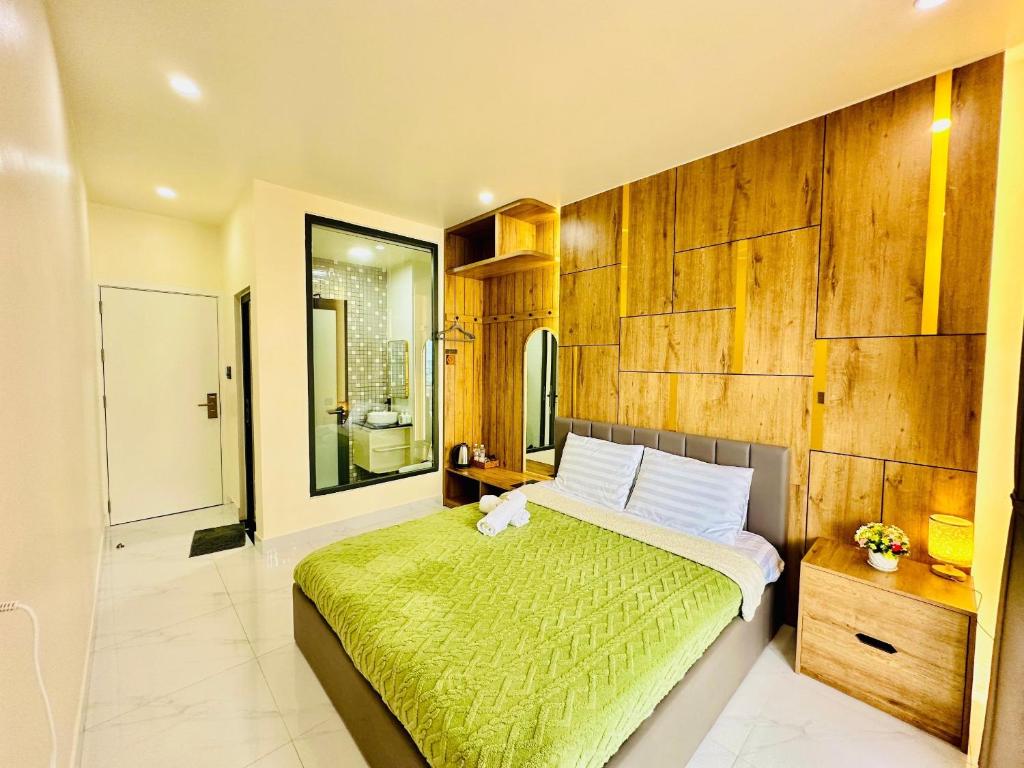 a bedroom with a large bed with a green blanket at Agape House Và Apartment in Da Lat