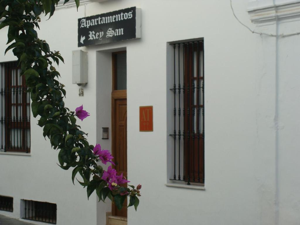 ein Schild an der Seite eines weißen Gebäudes mit lila Blumen in der Unterkunft Apartamentos Reysan in Vejer de la Frontera