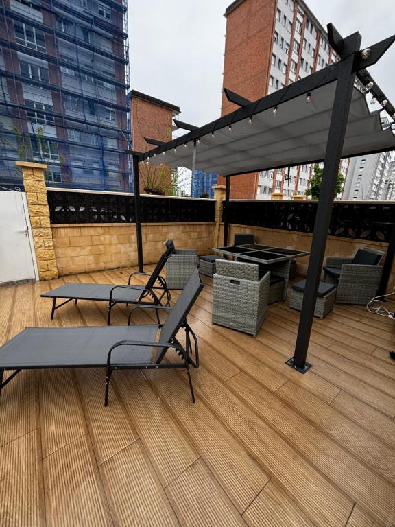 a rooftop patio with two chairs and a canopy at Apartamento Laredo con Terraza in Laredo