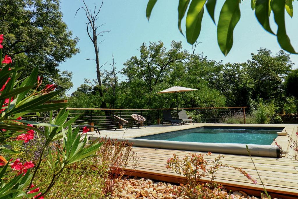 une piscine avec un parasol dans un jardin dans l'établissement La Maison de Pierrot, à Rignac