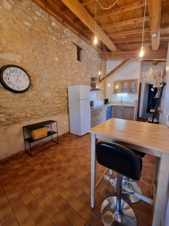 une cuisine avec une table et une horloge au mur dans l'établissement Charmante maison à la campagne, à Grane