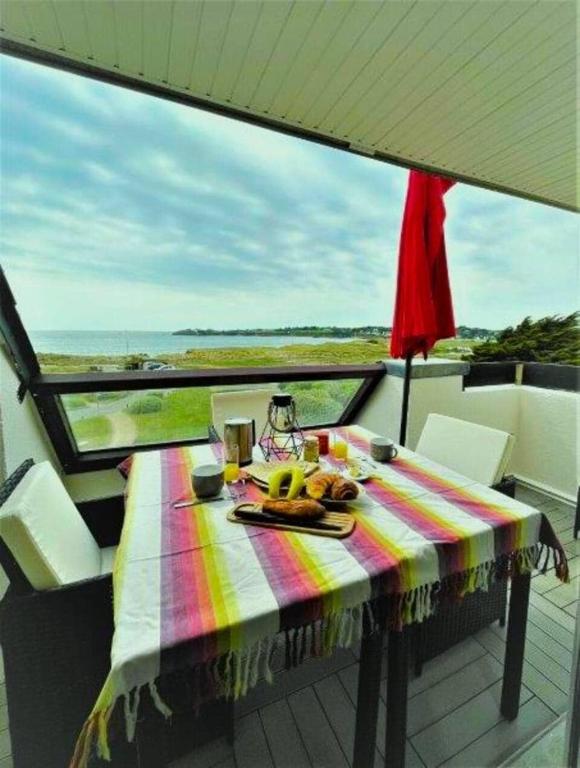 une table avec une assiette de fruits sur un balcon dans l'établissement Appartement face à la mer, à Guidel