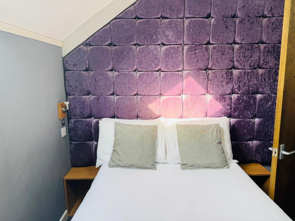 a bed in a room with a purple wall at Hotels 24-7 - The Old Victoria Hotel in Newport