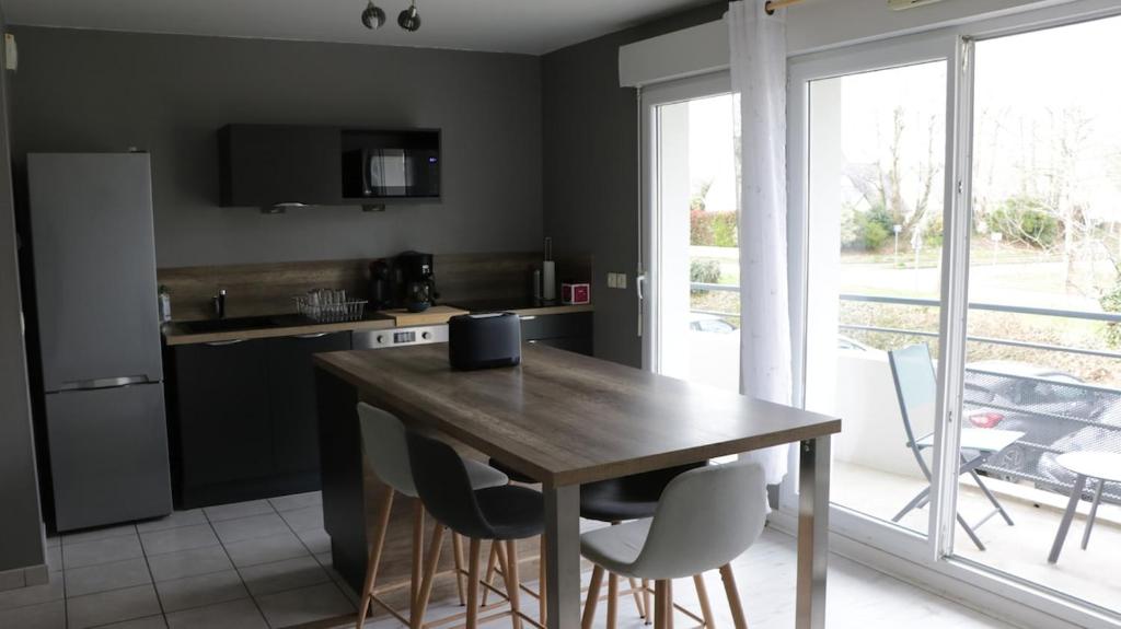 une cuisine avec une table en bois et quelques chaises dans l'établissement Apartment in a quiet residence, à Concarneau