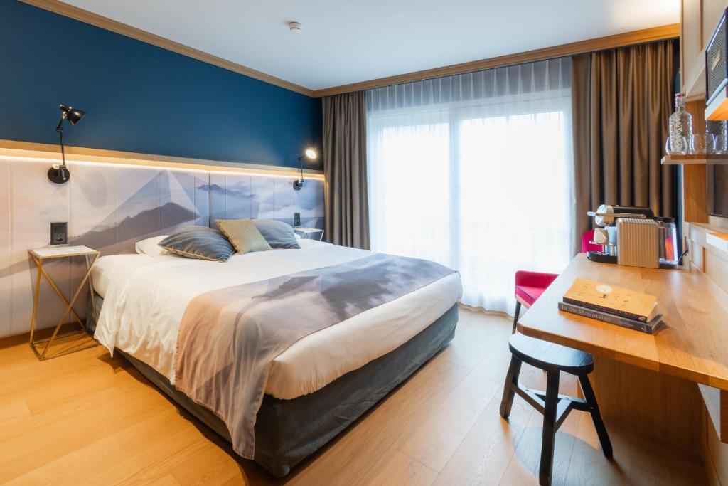 a bedroom with a large bed and a desk at Boutique Hotel Glacier in Grindelwald