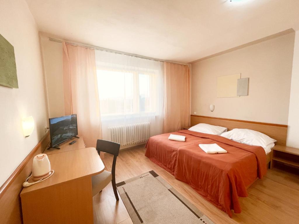 a bedroom with a bed and a desk and a television at Penzión na Sihoti in Trenčín