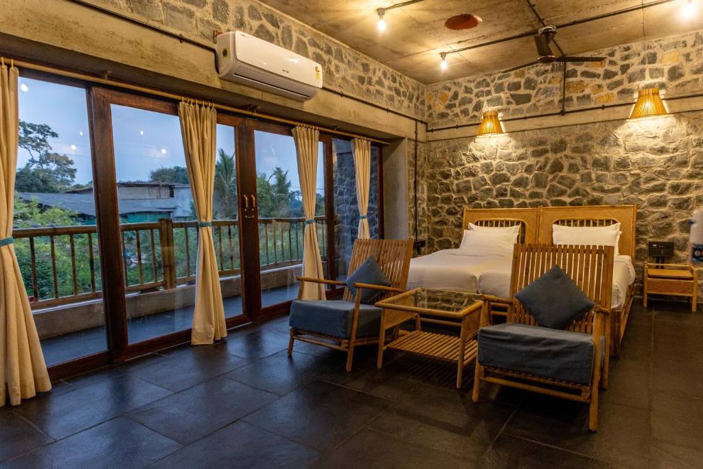 a bedroom with a bed and chairs and a balcony at Dang Forest Retreat in Bāori