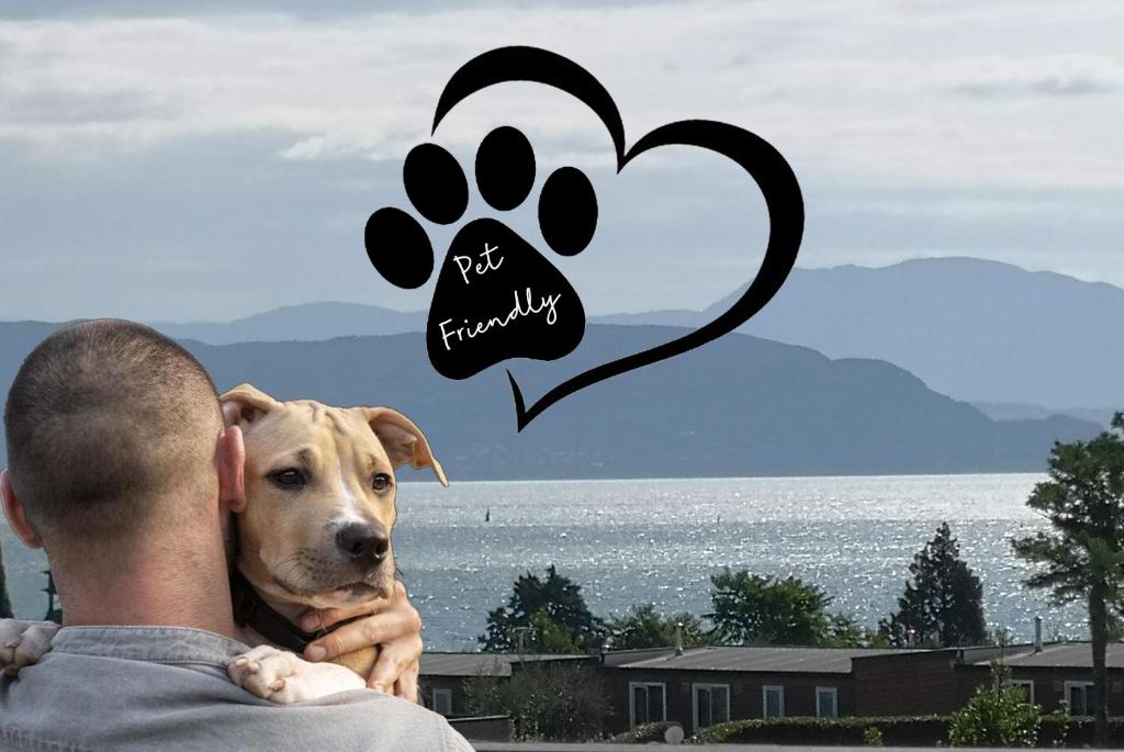 een man die een hond vasthoudt met een foto van zijn poot op zijn rug bij Note di lago in Manerba del Garda