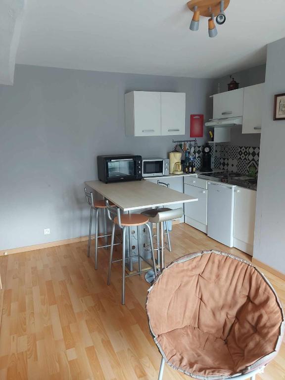 une cuisine avec une table et des chaises dans une pièce dans l'établissement appartement avec une chambre avec un grand lit , une d'enfant et un clic-clac dans la piece de vie, à Bazouges-sur-le-Loir