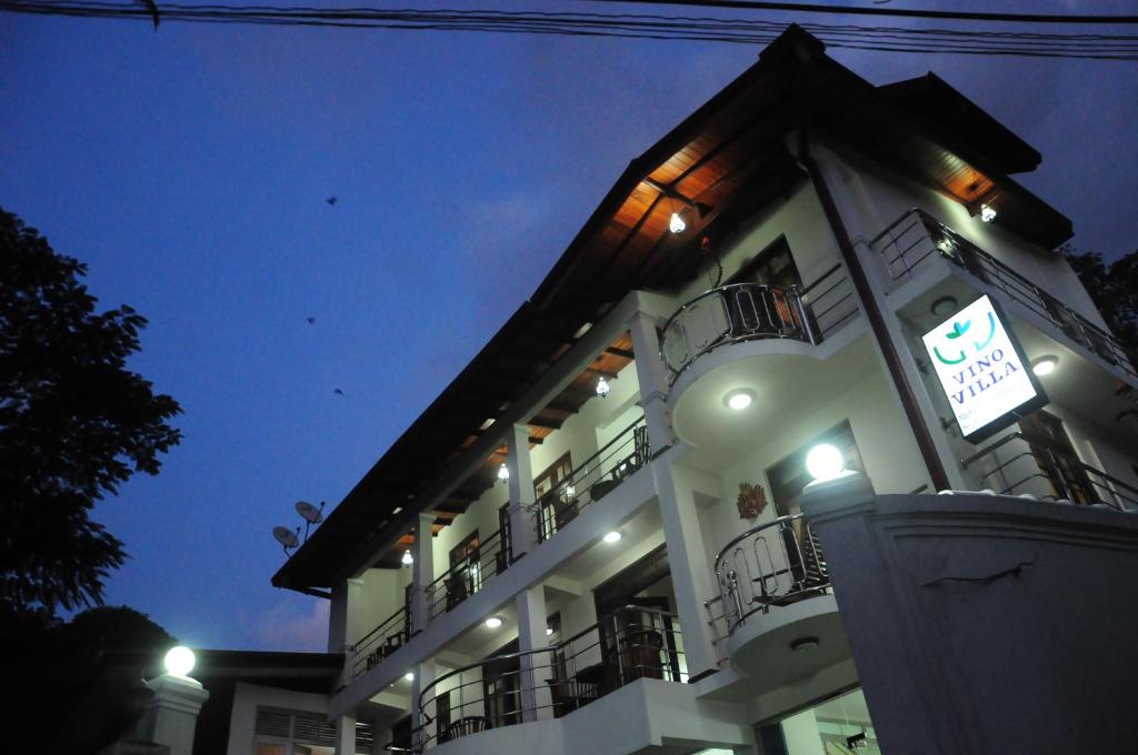 a white building with balconies and a sign on it at vino villa in Kandy