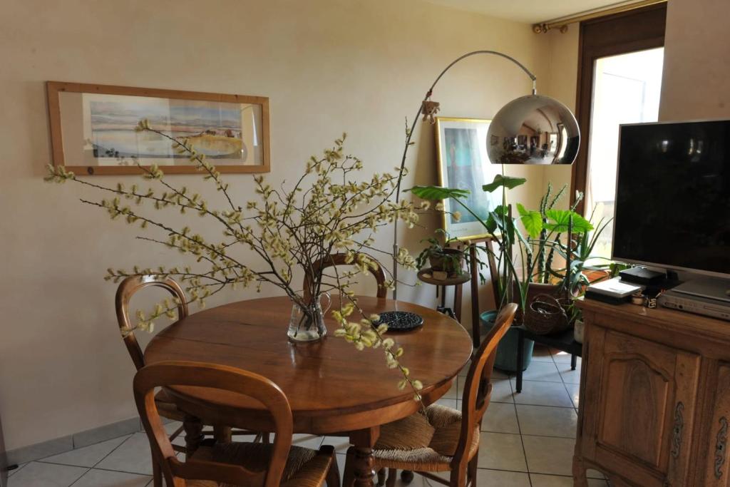 une table de salle à manger avec un vase de fleurs dessus dans l'établissement L'Alizée - Terrace overlooking the lake, à Aix-les-Bains