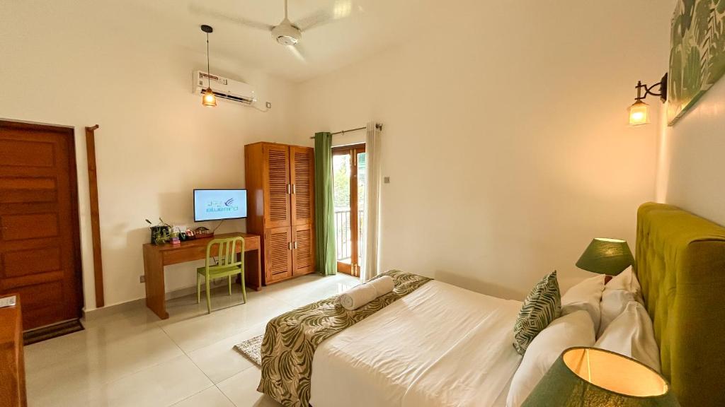 a bedroom with a bed and a desk in it at J leaf Hotel by Blue Bird in Negombo