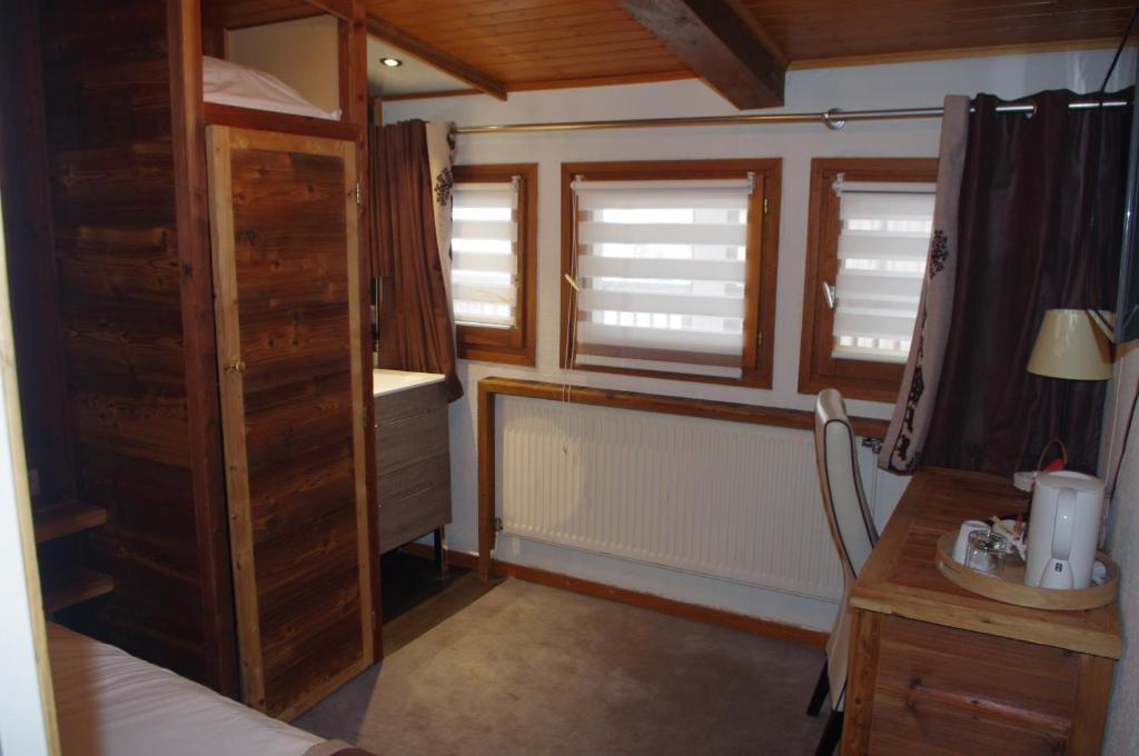 a small room with two windows and a desk at Hôtel Le Refuge in Tignes