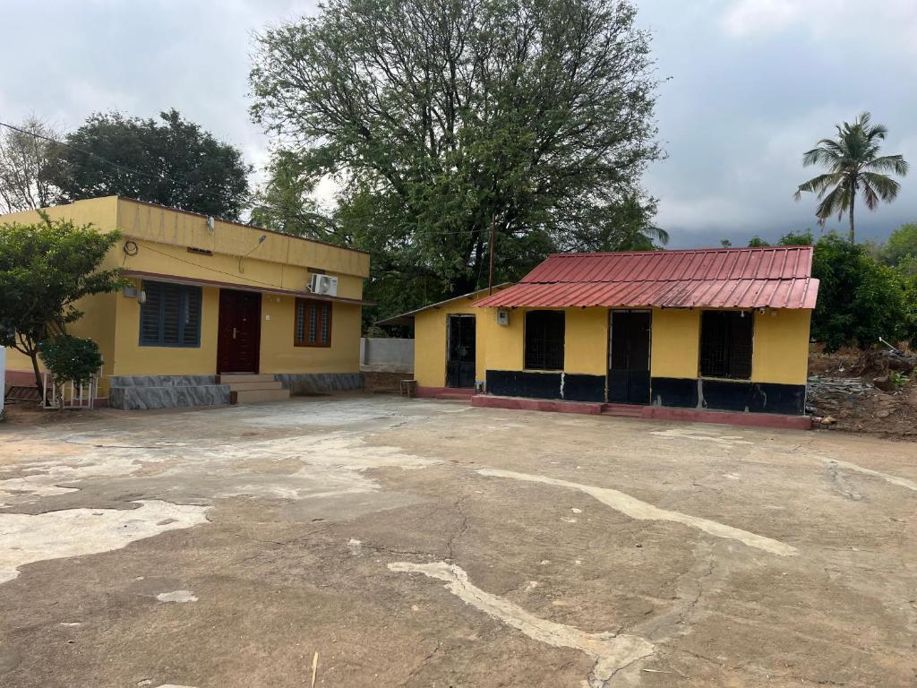 a yellow building with a red roof and a parking lot at Tharissu Potta Rassey Farm House in Kollengode