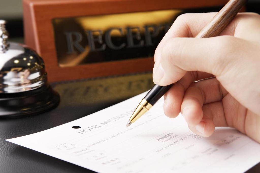 a person holding a pen on a piece of paper at Hotel Mystays Premier Akasaka in Tokyo