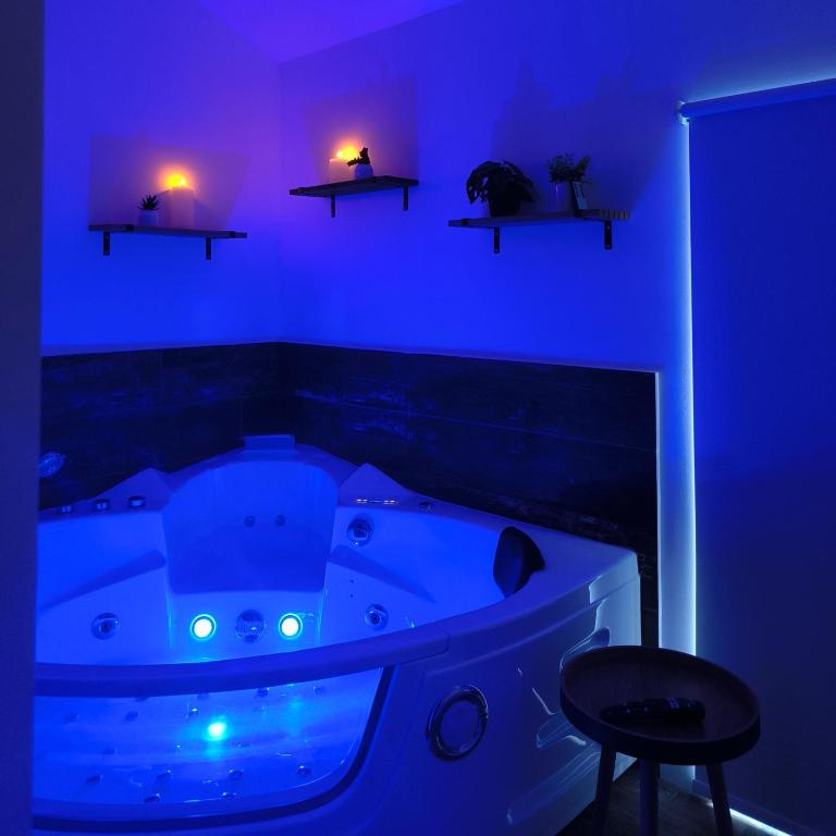 a blue room with a tub with a stool and lights at Ma douce Fenière in Saint-Rémy-de-Chargnat