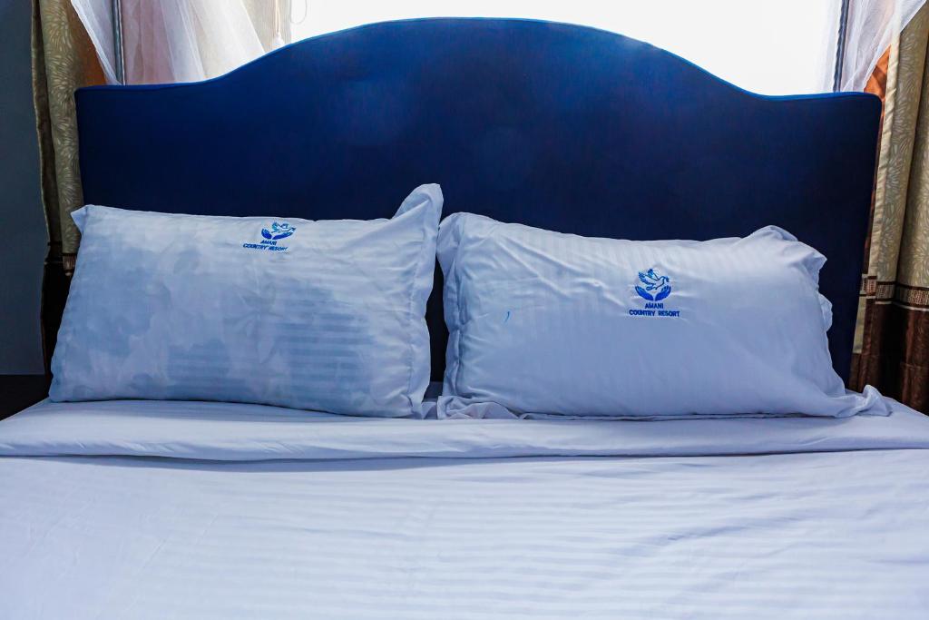 two pillows on a bed with a blue headboard at Amani Country Resort in Kampala