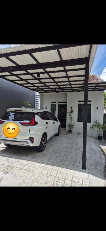 a white car parked under a pergola next to a house at Wima homestay batu in Batu