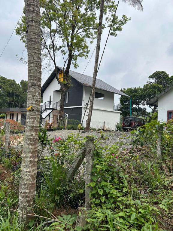 a house with trees and flowers in front of it at The Tea Leaf Cottage in Munnar