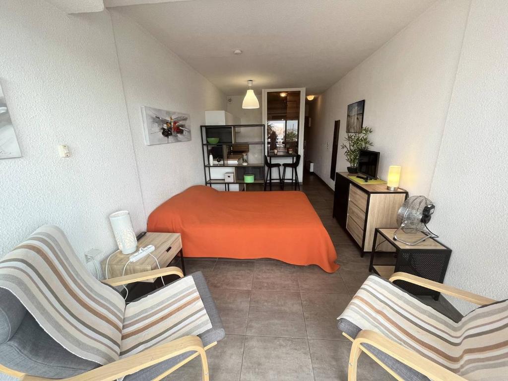- une chambre avec un lit et deux chaises dans l'établissement Studio 2 couchages Cap d'Agde naturisme CN040-722, au Cap d'Agde