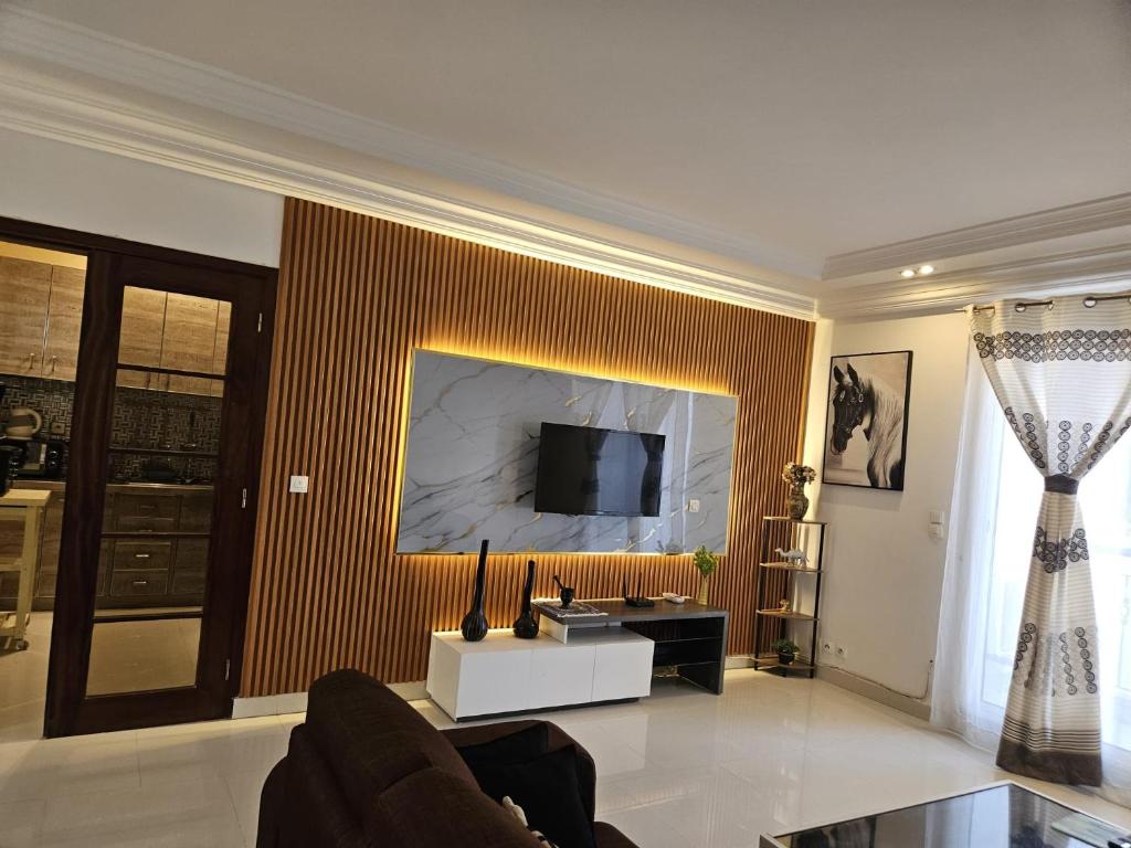 a living room with a couch and a tv on a wall at Keur Aïda Immeuble de standing in Dakar