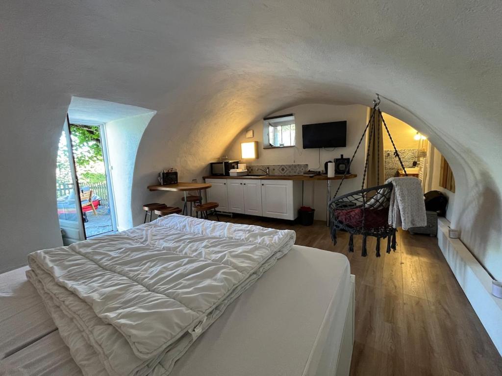 a bedroom with a white bed and a kitchen at Charmant studio, maison en pierre, terrace and garden in Veyras