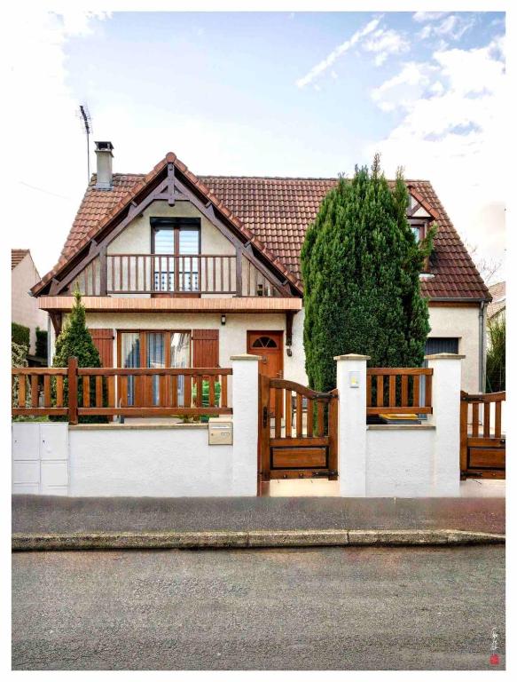 une maison avec une clôture blanche et des clôtures en bois dans l'établissement Charmante maison entre Paris et Disney, à Courtry