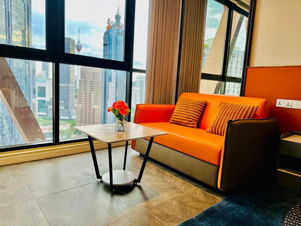 a living room with an orange couch and a table at Scarletz Suites KLCC by M Suites in Kuala Lumpur