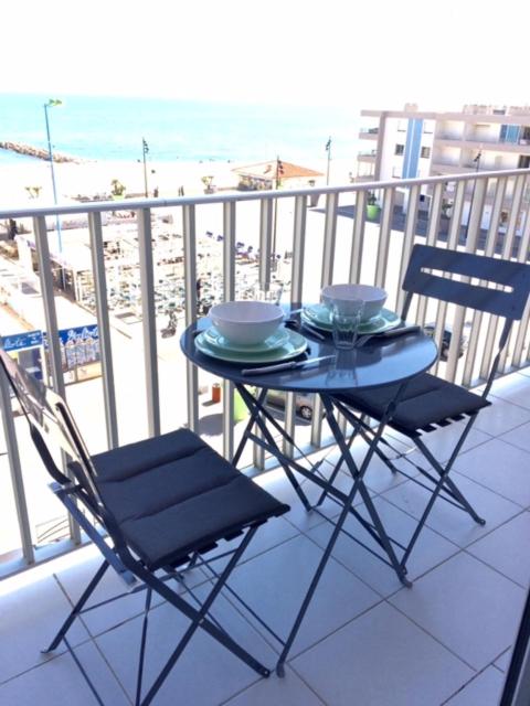 une table et des chaises sur un balcon avec la plage dans l'établissement Face mer, grand studio de 32m2, clim, wifi, parking, proche commerces, à Saint Cyprien Plage