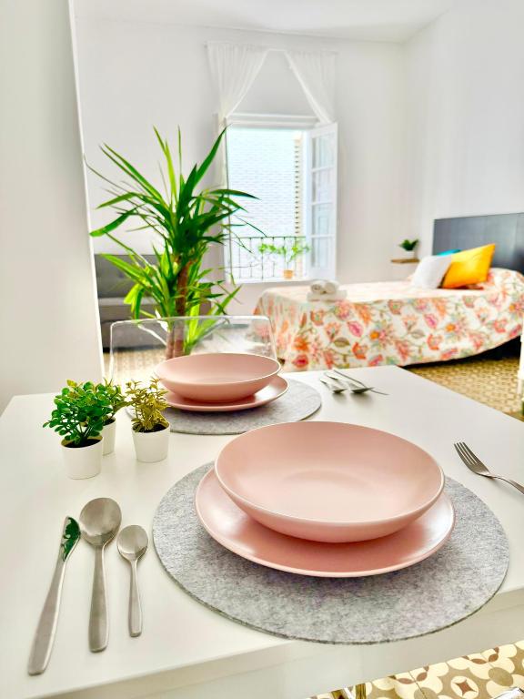 a table with two pink plates and spoons on it at Apartamento centro 1A in Huelva