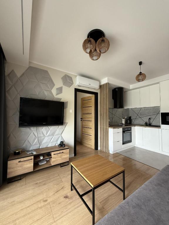 a living room with a television and a table in it at Ogrodowa70 Apartment in Sztutowo