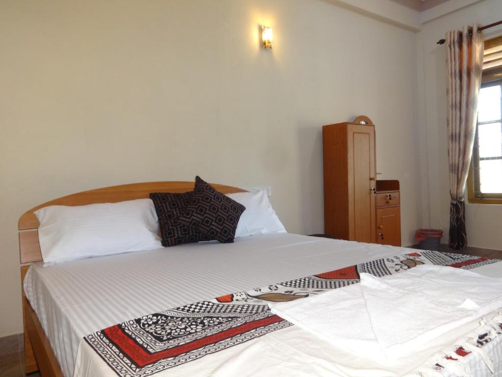 - une chambre dotée d'un grand lit avec des draps et des oreillers blancs dans l'établissement Hotel Alas Garden, à Trincomalee