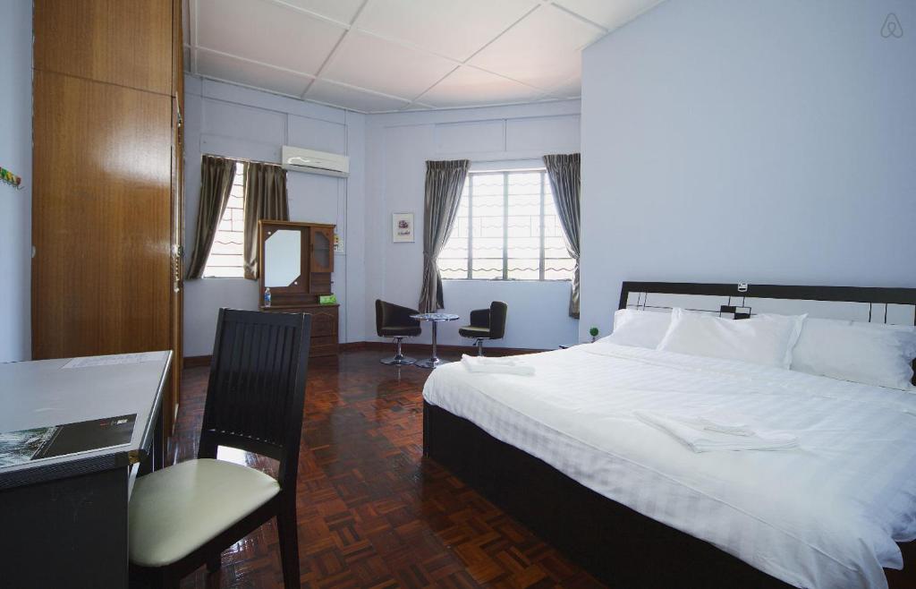 1 dormitorio con 1 cama blanca grande y escritorio en Hin Loi Guesthouse, en Kota Kinabalu