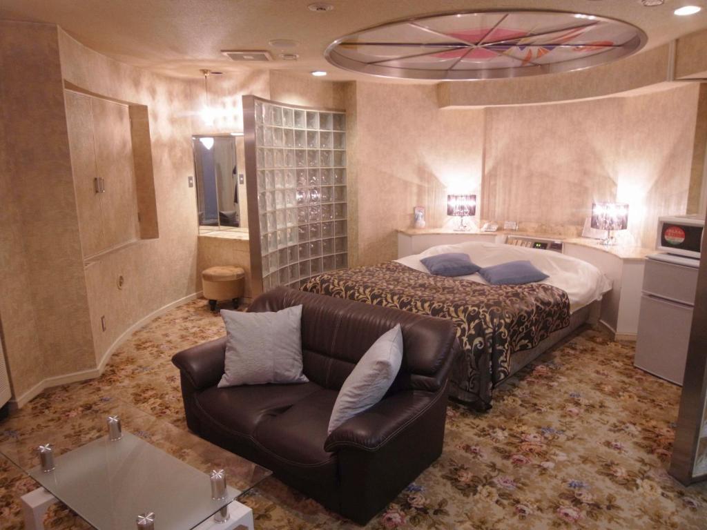 um quarto com uma cama e um sofá em Hotel Plage (Adult Only) em Yokohama