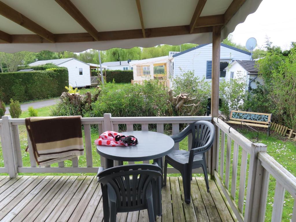 un patio avec une table et des chaises sur une terrasse dans l'établissement Mobile home dans un camping à saint Arnoult, à Saint-Arnoult