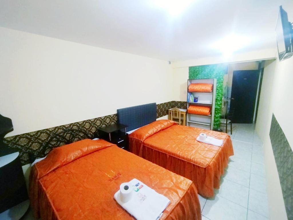 Samay Misti ApartHostal في أريكيبا: سريرين في غرفة الفندق بملاءات برتقالية