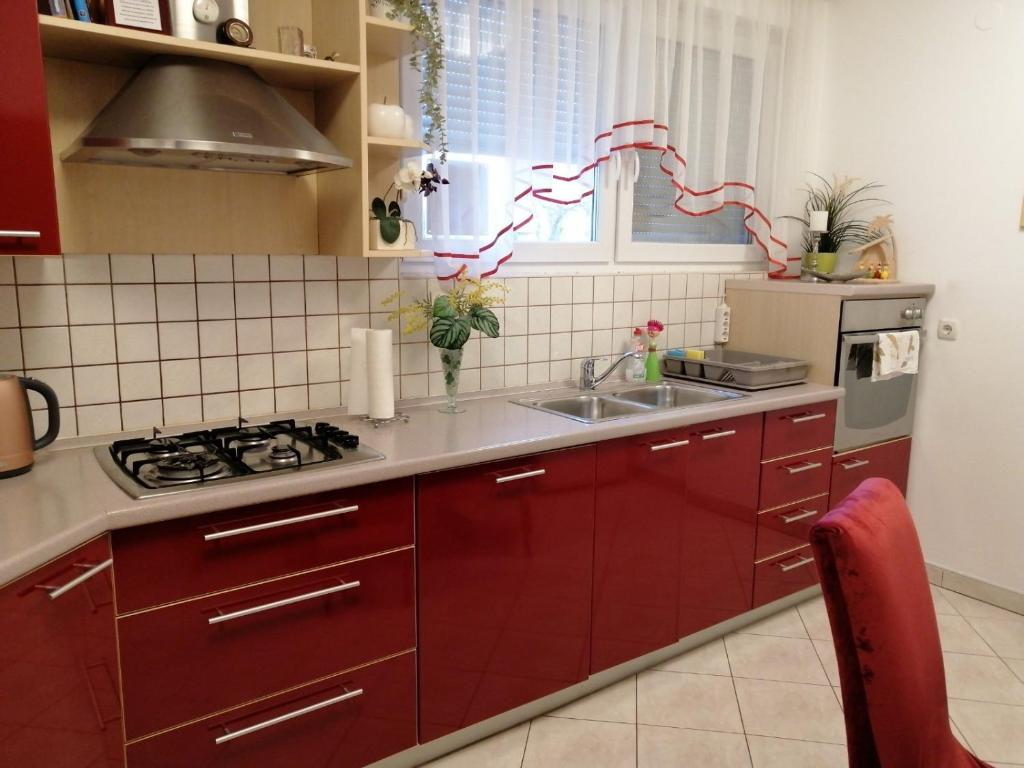 a kitchen with red cabinets and a sink at Apartment Meli Varazdin in Varaždin