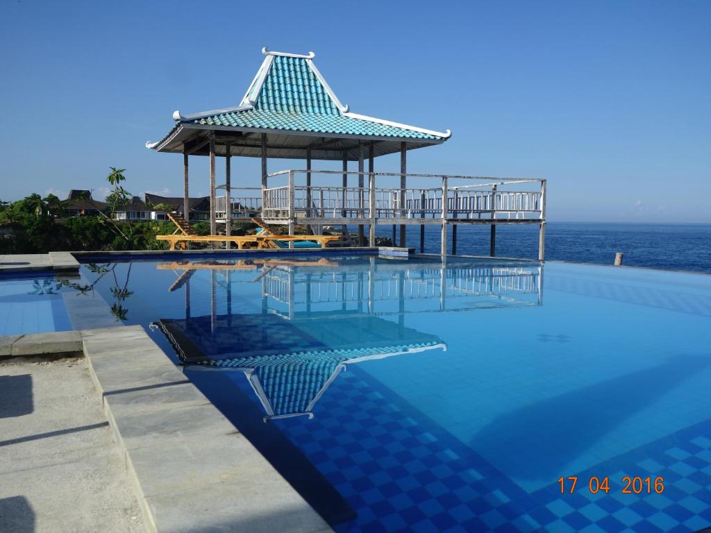 a swimming pool with a gazebo next to the ocean at Cliff Park Lembongan in Nusa Lembongan