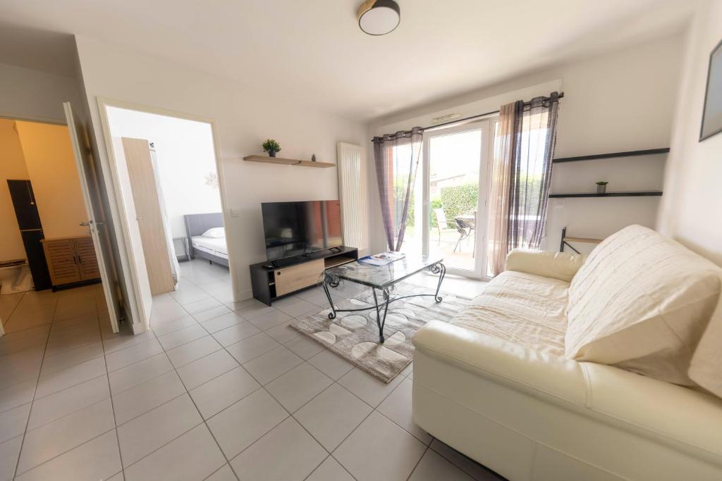 un salon avec un canapé et une télévision dans l'établissement Charmant T2-10 min de la plage, à Saint-Martin-de-Seignanx